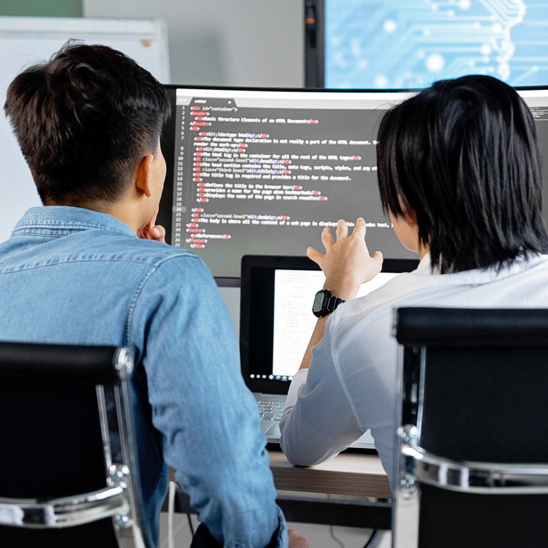 Two people looking at code on a computer screen